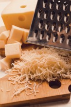 Grated cheese, Maasdam, on a cutting board, grater and cheese knife, close-up, no people