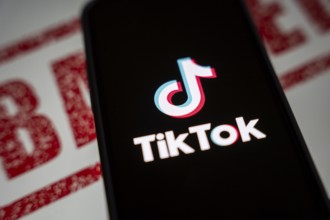 In this photo illustration, logo of Tiktok is displayed on mobile phone screen next to ban sign, in