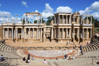 Ancient Roman theatre with ruins and columns in the background, people exploring the historic site