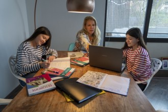 Homeschooling, during the lockdown in January 2021, mother helps her two daughters, at home,