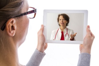 Symbolic image of telemedicine, patient speaking to a doctor in a video conference from home