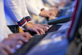 Young people, children play on many keyboards, simultaneously, electronic clarinet, at a concert