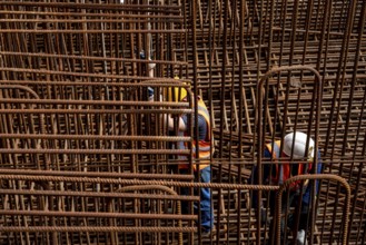 Construction site, reinforced concrete construction site, workers erect a mesh of reinforcing bars,