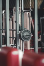 Close-up of a modern fitness machine with dumbbells and steel structures in the background,