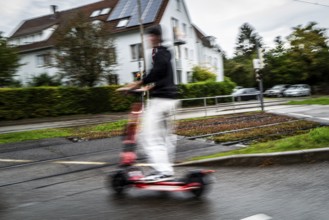 Person riding an e-scooter in an urban environment with blurred background