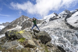 Mountaineer jumping from rock to rock, high alpine glaciated mountain landscape, La Jonction,