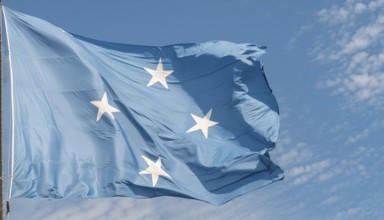 The flag of Micronesia, Pacific Islands, fluttering in the wind, isolated against a blue sky