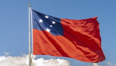 The flag of Samoa, fluttering in the wind, isolated against a blue sky