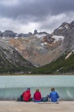 Hikers sitting on the shore of the glacial lake Laguna Esmeralda, Tierra del Fuego Island,