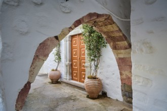 A historic stone Tor tor with plant pots and arches on a Greek island leading into a quiet