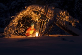 Man grilling sausage at a campfire under a snowy pine tree, Gällivare, Norrbotten, Lapland, Sweden,