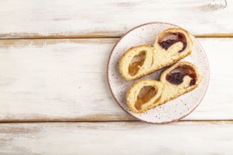 Homemade sweet bun with apricot jam on white wooden background. top view, flat lay, copy space