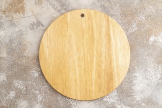 Empty round wooden cutting board on brown concrete background. Top view, close up, flat lay