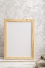 White wooden frame mockup with linen textile on gray concrete background. Blank, vertical