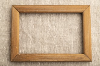 Wooden frame on smooth white linen tissue. Top view, flat lay, natural textile background and