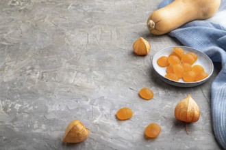 Jelly pumpkin candies on gray concrete background and blue linen textile. copy space, side view.