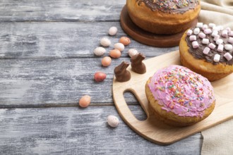 Homemade glazed and decorated easter pies with chocolate eggs and rabbits on a gray wooden