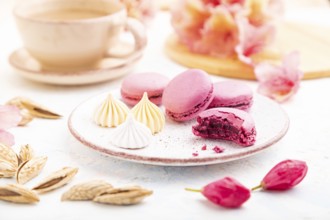 Purple macarons or macaroons cakes with cup of coffee on a white concrete background decorated with