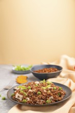 Quinoa porridge with green pea and chicken on ceramic plate on a gray concrete background and