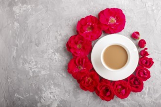 Red rose flowers in a spiral and a cup of coffee on a gray concrete background. Morninig, spring,