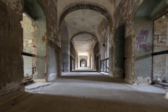 Long empty corridor with peeling paint and graffiti stretching into the distance,