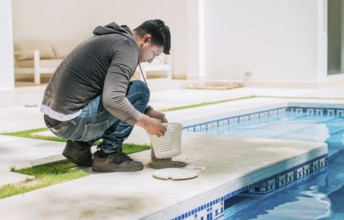 Worker removing trash from swimming pool filter basket. Man cleaning swimming pool garbage filter