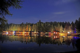 Illuminated little holiday cabins standing by a lake on a campsite, stars, romance, Quebec, Canada,