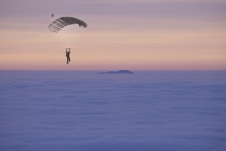 Paraglider Flying over a Cloudscape with a Mountain Peak in Sunset in Ticino, Switzerland, Europe