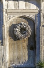 Silver white Christmas wreath on ancient old door in Lavenham, Suffolk, England, UK