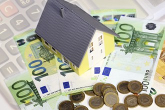 Concept photo with model house, euro notes and coins