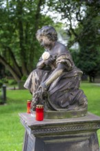 Figure in a cemetery, old gravestone, with flower and grave light, North Rhine-Westphalia, Germany,