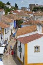 Tourists walk through a cobbled street in the old town with white and yellow facades, view from