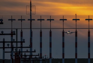 Runway lighting, approach aids, at Düsseldorf International Airport, sunset, aircraft approaching