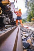 Railway worker in safety clothing works on a railway vehicle and fixes loose parts, surrounded by