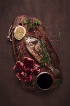 Fried dorado fish, with spices and herbs, on a wooden board, pomegranate sauce, close-up, no people