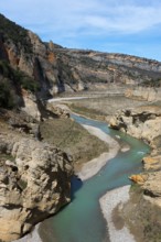 A winding river flows through a rocky gorge in a mountainous landscape under a clear sky, Noguera