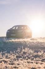 A car parked in the frosty terrain with the sun rising in the background, car sharing, electric