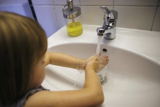 Symbolic photo: A small child washes its hands with soap and water at the bathroom sink. Berlin, 21