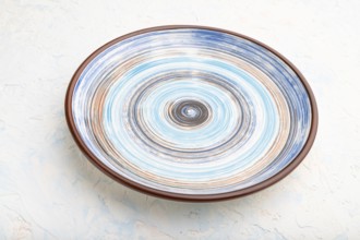 Empty blue ceramic plate on white concrete background. Side view, close up