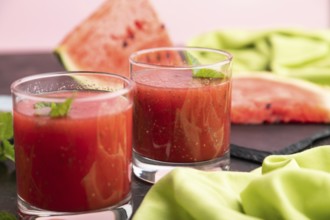 Watermelon juice with chia seeds and mint in glass on a black concrete background with green