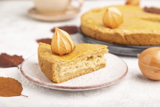 Autumn onion pie decorated with leaves and cup of coffee on gray concrete background. Side view,