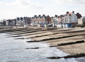 Sandy beach concrete groyne sea defences and historic buildings on the seafront on a sunny day in