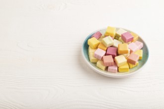 Various fruit jelly chewing candies on plate on white wooden background. apple, banana, tangerine,