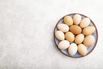 Pile of colored chicken eggs on plate on a gray concrete background. top view, flat lay, copy space