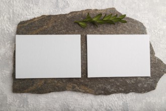 White paper business card, mockup with natural stone and boxwood branch on gray concrete background