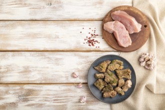 Stewed turkey fillet with garlic on white wooden background and linen textile. Top view, flat lay,