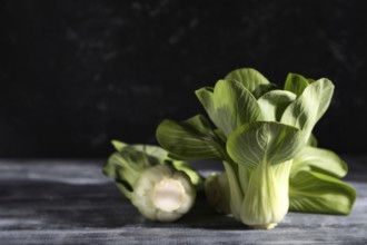 Fresh green bok choy or pac choi chinese cabbage on a gray wooden background. Hard light, contrast,