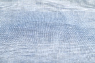 Fragment of smooth blue linen tissue. Side view, natural textile background and texture