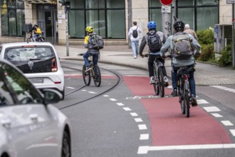 Cyclist in the city centre, red marked bicycle lane, cars pass close by, Mülheim an der Ruhr, North