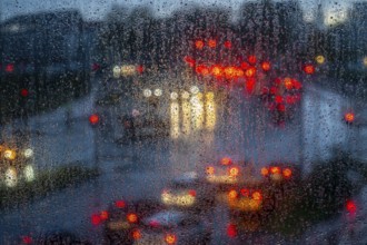 Rainy weather, road traffic, raindrops on a window pane, behind, blurred, lights of vehicles on a